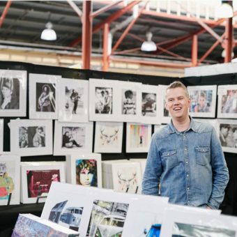 Man standing in shop with various prints